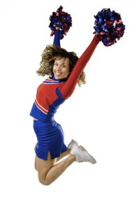 Uniformed cheerleader jumps high in the air